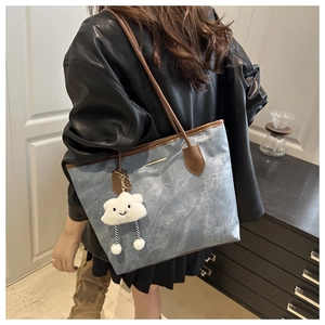 Detailed shot of large denim tote bag with leather trim and cute plush cloud charm