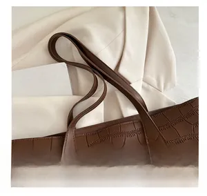 Close-up of deep brown crocodile embossed leather handbag with reinforced stitching details