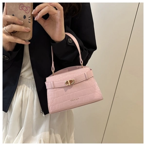 Détail du sac à main rose avec motif crocodile et fermoir métallique doré brillant