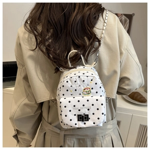 Mini sac à dos à pois blancs avec bandoulière chaîne porté par un mannequin en intérieur