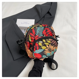 Detail of trendy crossbody bag with vibrant colorful leaf patterns and front zipper pocket