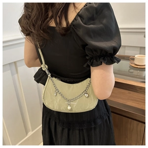 Detail of light green nylon shoulder bag with silver chains and star charms on model