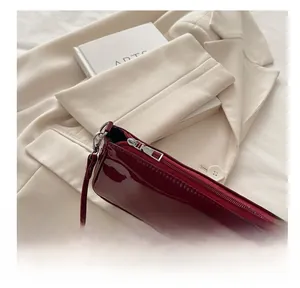 Detail of burgundy patent leather shoulder bag with smooth silver metal zipper closure