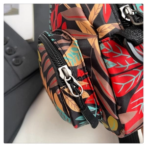 Detail of canvas shoulder bag with vibrant tropical leaf print and dual zipper pockets