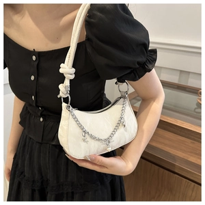 Detail of white half-moon bag with star charms and chain on black dress