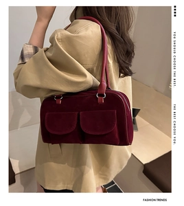 Détail du sac polochon en daim bordeaux avec doubles poches sur un trench-coat