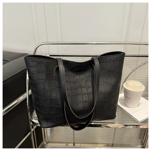 Gros plan d'un grand sac cabas noir avec texture crocodile et longues anses d'épaule