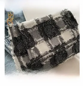 Detail of black and white tweed crossbody bag featuring frayed edges and gold chain strap
