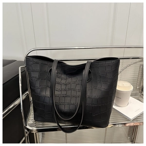 Close-up of black crocodile pattern leather tote bag on a modern display shelf