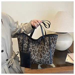 Close-up of leopard print tote bag with black leather straps and matching pouch accessory