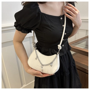 Detail of white crescent shoulder bag with silver chain, star and pearl charms on model