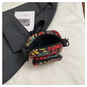 Top view of mini floral canvas crossbody bag with double zippers and leaf patterns