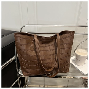 Close-up of brown crocodile texture on large tote bag displayed on a metal shelf
