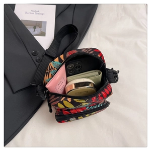 Detail of tropical leaf print crossbody bag showing multi-layer zippers and internal storage