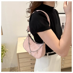 Pink hobo bag with silver chain and pearl pendant shown in an interior setting