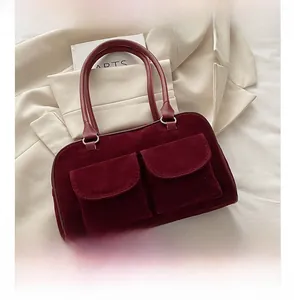 Deep red velvet handbag detail with dual front pockets and size comparison to a smartphone