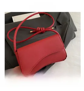 Detail of red crossbody bag showing textured saffiano leather and gold metal buckle