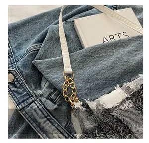 Detail of dark gray plaid denim handbag featuring raw edges and gold chain link strap