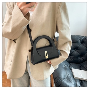Chic black handbag with a unique semicircular handle and gold geometric lock detail