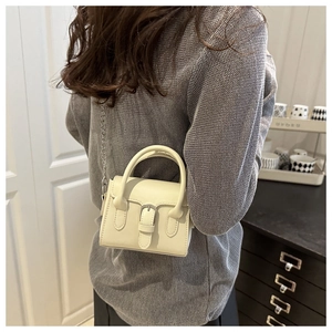 Detailed view of cream mini handbag with silver chain strap and metal buckle on model
