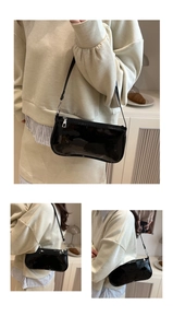 Close-up detail of glossy black patent leather shoulder bag with silver metal zipper
