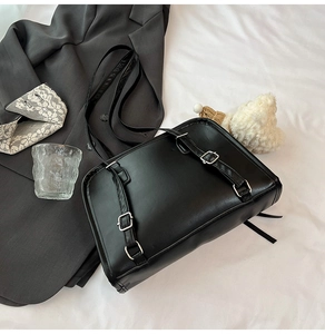 Detail of minimalist black leather bag with silver metal buckles and double straps