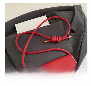 Detail of red crossbody bag featuring textured leather and unique spiral knot shoulder strap