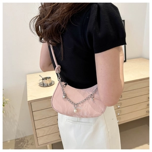 Detail of pink pleated underarm bag featuring a delicate metal chain and pearl charm
