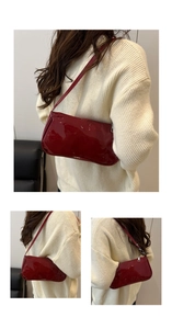 Detail of a red patent leather baguette bag with a sleek silver zipper and slim strap