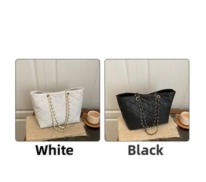 Quilted tote bags in black and white with chain straps shown in a lifestyle setting