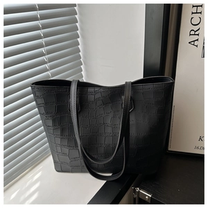 Close-up of black tote bag showing detailed faux crocodile texture and slim handles