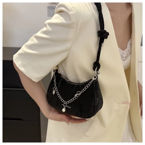 Detail of black crescent shoulder bag featuring silver chain and pearl pendant charm