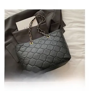 Close-up of black quilted tote bag featuring a diamond pattern and elegant metal chain strap