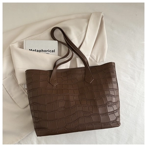Gros plan sur la texture gaufrée crocodile marron foncé d'un grand sac cabas en cuir
