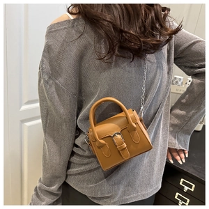 Brown matte leather mini crossbody bag with silver chain strap shown on a model