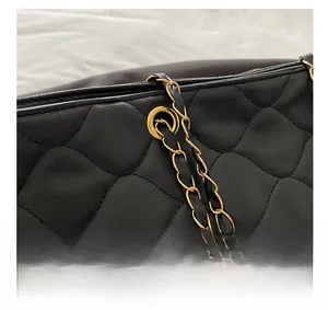 Detail of the golden hardware chain and black quilted leather pattern on the tote bag