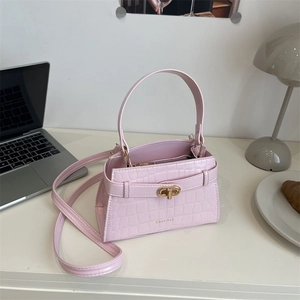 Sac à main rose à motif crocodile avec fermoir doré dans un décor de bureau moderne
