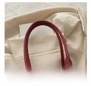 Close-up of burgundy velvet pillow bag featuring leather handles and silver metal hardware