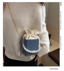 Close-up of suede crossbody bag with elegant pearl handle and gold chain strap