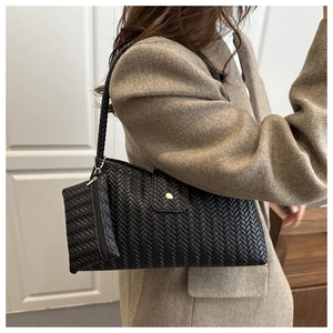 Detail of woven black leather shoulder bag featuring intricate Intrecciato craft style