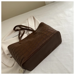 Vue détaillée de la texture gaufrée crocodile marron foncé sur un grand sac cabas