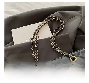 Detail of leather chain strap and quilted texture on a large black tote bag