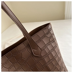 Détail du motif crocodile embossé et des coutures fines sur le sac fourre-tout en cuir marron