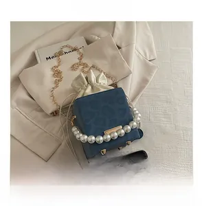 Detail view of navy blue velvet bucket bag with pearl handle and metal chain strap