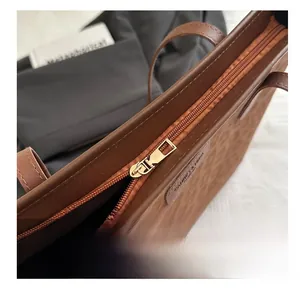 Detail of smooth gold zipper and animal texture embossing on brown tote bag