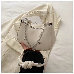 Close-up of white crescent bag with silver star charms and knotted strap detail