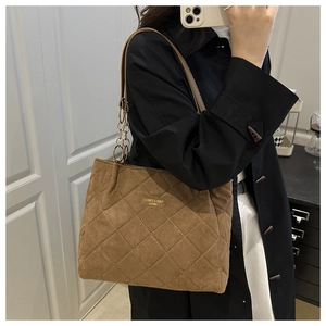 Detailaufnahme der braunen gesteppten Tragetasche aus Wildlederimitat mit Metalllogo und Kette
