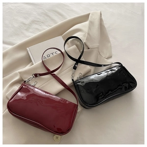 Close-up of glossy patent leather shoulder bags in black and burgundy with silver zippers