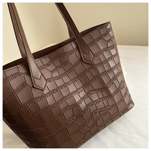 Détail d'un sac cabas marron avec gaufrage crocodile et perforations laser de précision