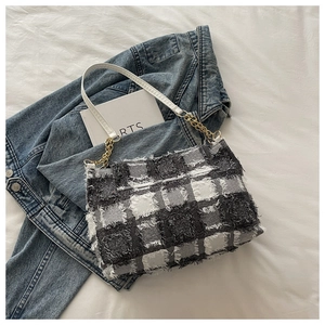 Detailed close-up of plaid tweed shoulder bag with gold chain and white leather strap